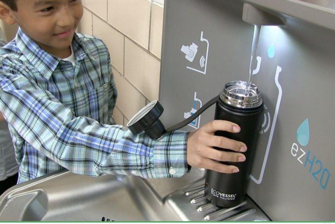 Child Filling water bottle at office water dispenser 
